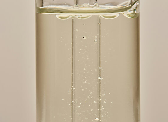 A close-up of a clear liquid serum in a glass bottle